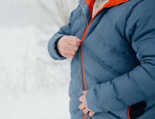 Ilustračný stock: pérová outdoor bunda v zime, střízlivý záber, bez loga TNF/Patagonia a bez fashion lookbooku.