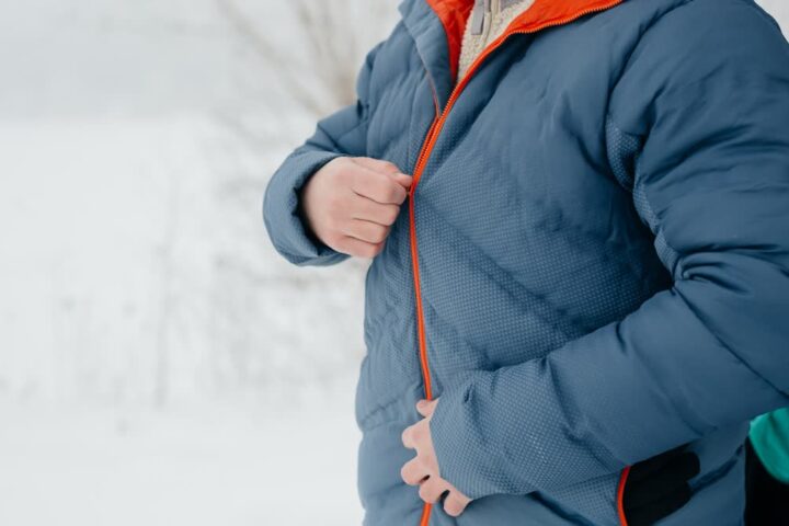 Ilustračný stock: pérová outdoor bunda v zime, střízlivý záber, bez loga TNF/Patagonia a bez fashion lookbooku.