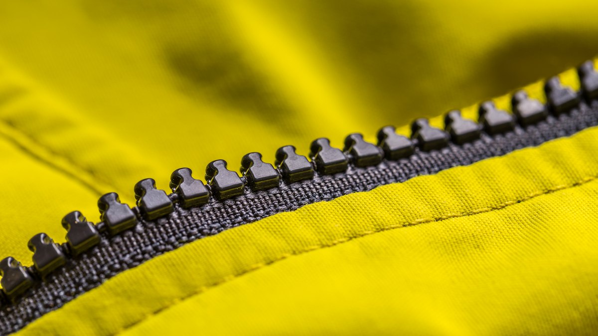 Ilustračný stock: outdoor bunda a textilný detail na lavici, bez čitateľnej značky TNF/Patagonia a bez hero tváre modelu.