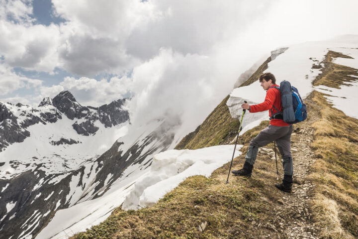 Ilustračný stock: turista vo vetrovke na horskom hrebeni nad dolinou civilne, bez loga outdoor značky.