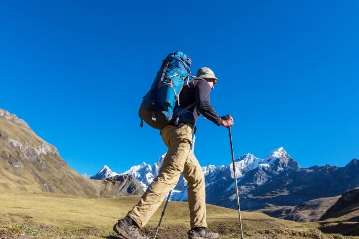 Ilustračný stock: turista v horách nad 2500 metrov s batohom a trekkingovými palicami, civilne, bez loga