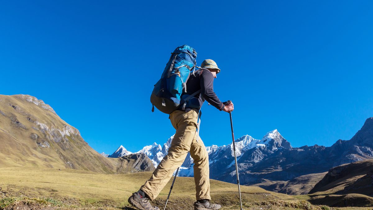 Ilustračný stock: turista v horách nad 2500 metrov s batohom a trekkingovými palicami, civilne, bez loga